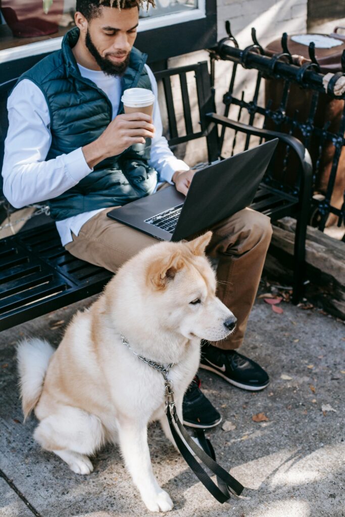 A freelancer enjoying a coffee, doing work, and spending time with his dog.